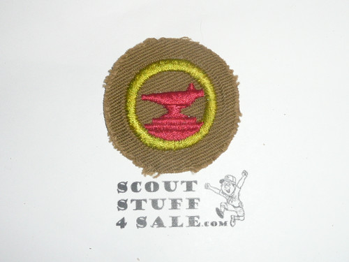 Blacksmithing - Type C -  Tan Crimped Merit Badge (1936-1946), a little paper on the back