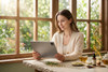 a woman reading a tablet by a sunlit window