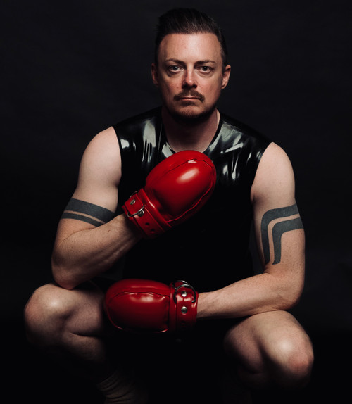 Model wearing Restrict Gear padded rubber bondage mitts in red latex