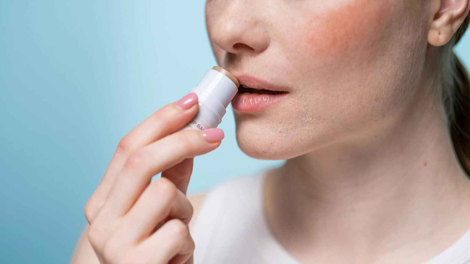 A woman applying lip balm as part of her daily self-care.