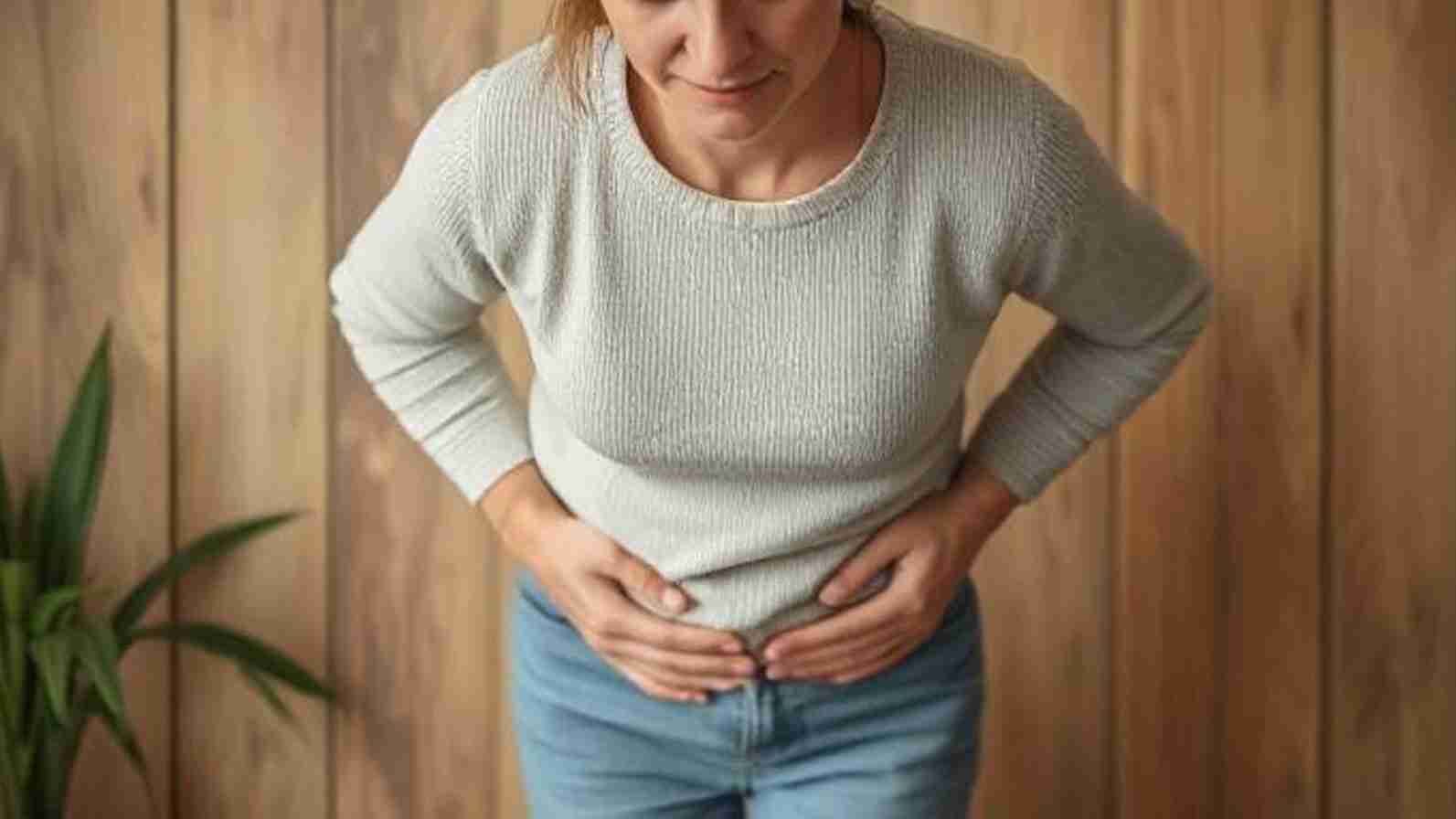 A woman grimaces in discomfort, holding her stomach, indicating pain due to constipation.