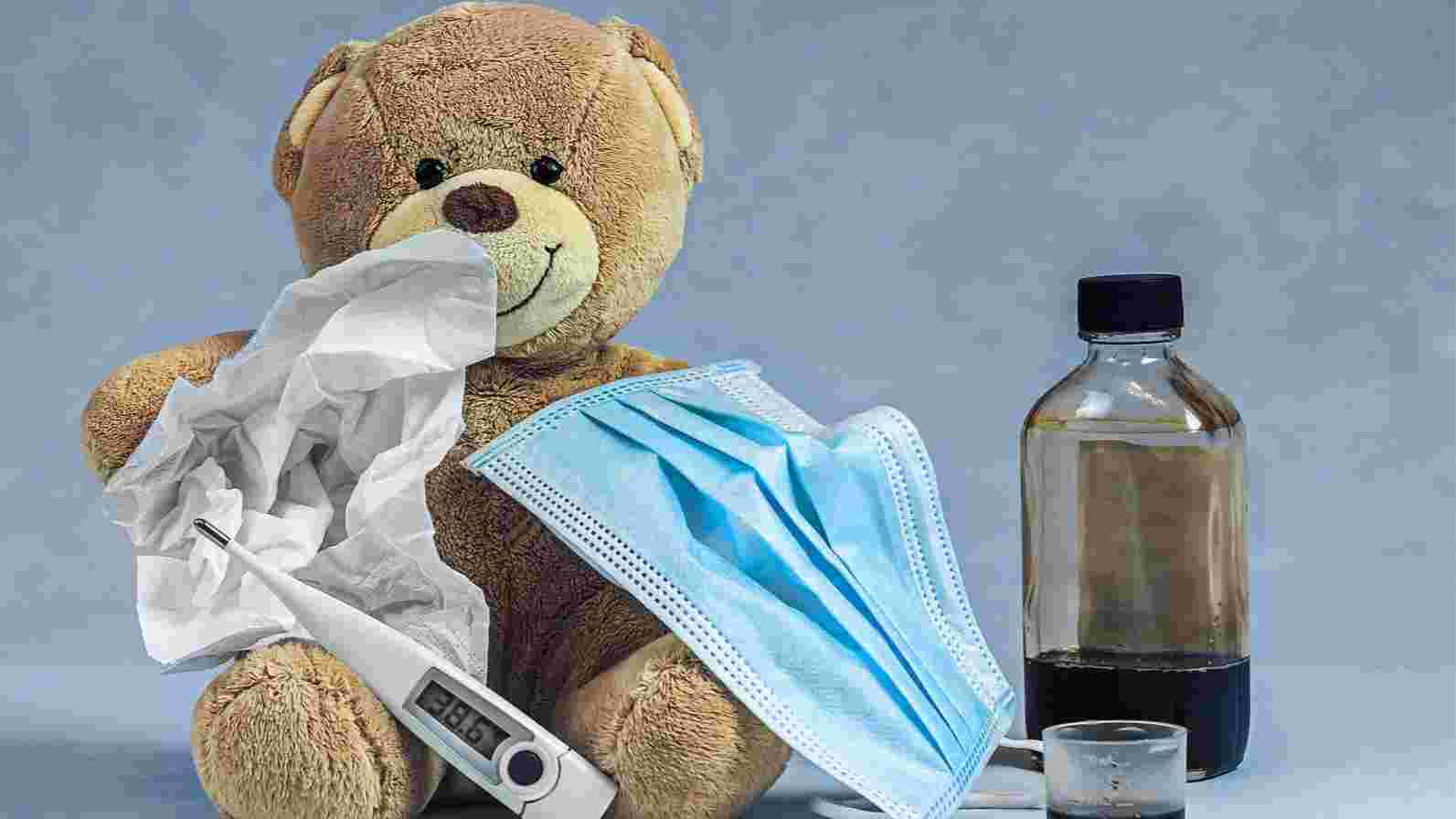 A teddy bear  holding tissue and a mask, promoting health awareness for children during cold and flu season.
