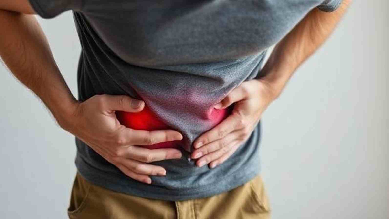 A man with his hands on his stomach, appearing uncomfortable, likely due to digestive distress or diarrhea.