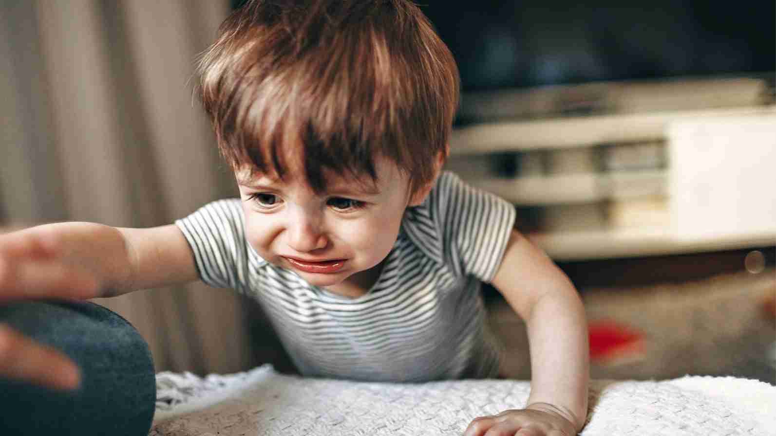 A young child is on the floor, crying, showcasing the raw emotions associated with children's pain and distress.