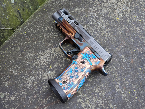 A photo of the sig sauer P320 AXG equipped with Solid Copper Kraken grips and backstrap, made by Vytal Manufacturing and finished in the seafoam blue hue of the Shipwreck forced oxidation patina.