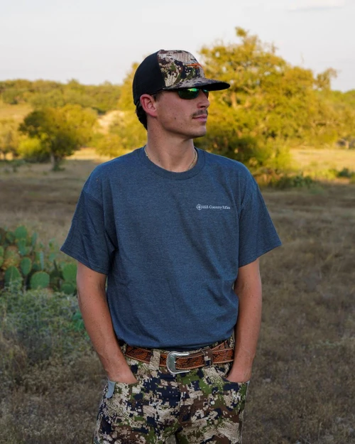 HCR T-Shirt - Navy, a navy blue casual T-shirt worn by a man standing outdoors in a natural setting.