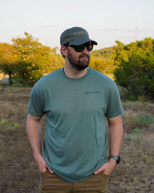 HCR T-Shirt - Olive, man wearing olive green T-shirt with 'Hill Country Rides' logo on chest, outdoors in nature setting.
