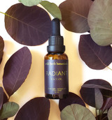 A 30 mL amber glass bottle of Radiant CBD Face Oil by Wild Herb Botanicals, featuring a minimalist label and dropper cap, set against a neutral background.