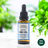 Humble Collective THC-Free CBD Oil bottle labeled "Unflavored" with 1000 mg CBD. Blue label design with dropper top, shown in natural light with green plant background. Made with CBD isolate and MCT oil.