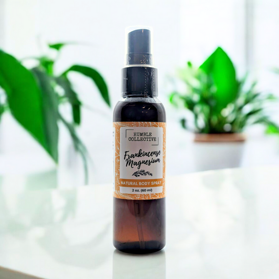 Humble Collective Frankincense Magnesium Natural Body Spray – 2 oz amber bottle with orange botanical label, designed for topical magnesium delivery and relaxation, displayed on a white surface with green plant in the background. Humble Collective Frankincense Magnesium Natural Body Spray – 2 oz amber bottle with orange botanical label, designed for topical magnesium delivery and relaxation, displayed on a white surface with green plant in the background.