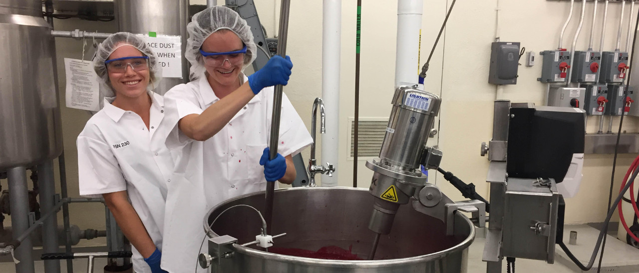 Cal Poly student employees stirring jam in the industrial sized mixer