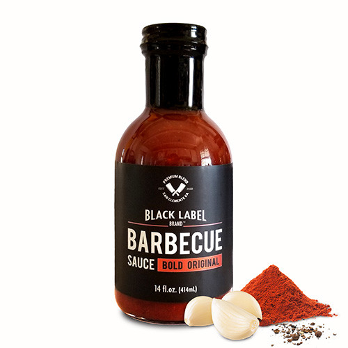 A bottle of Black Label BBQ Original sauce with piles of spices by the side