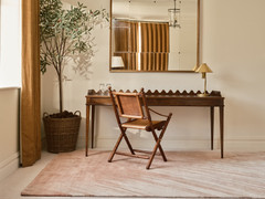 David Rockwell Splash Salmon rug in a bedroom study corner with a scalloped desk, brass lamp and mustard linen curtains