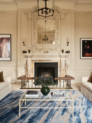 David Rockwell Fjord Frost rug before an ornate marble fireplace in a drawing room with cream sofas and a glass coffee table