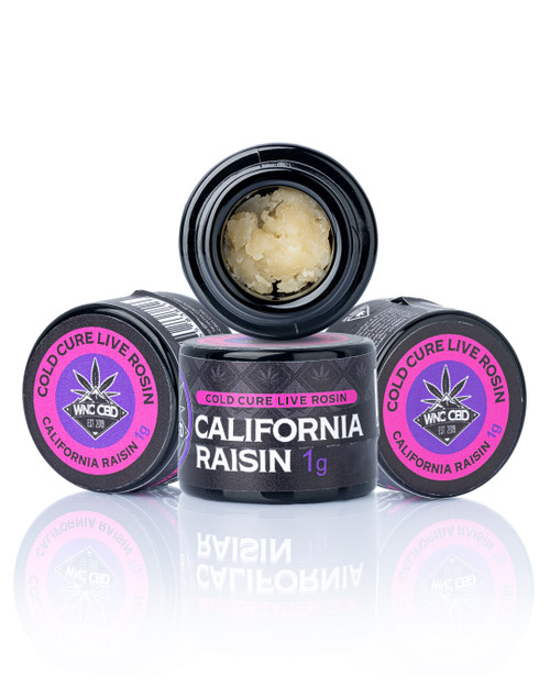 California Raisin Cold Cure Live Rosin in black jars with purple labels, creamy concentrate inside.