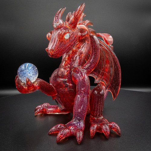 Scoz Red/Magenta Mini Dragon glass figurine with intricate detailing, holding a blue orb on a dark background.