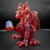 Scoz Red/Magenta Mini Dragon glass figurine with intricate detailing, holding a blue orb on a dark background.