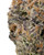 Close up of a dense Tropical Runtz cannabis bud displaying bright green and purple hues, orange pistils, and a heavy frost of crystalline trichomes