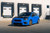 A sleek Subaru WRX STI is fully wrapped in KPMF's Gloss Atlantic Pearl vinyl. The vibrant blue hue with a pearlescent finish catches the light, creating a dynamic, shimmering effect that accentuates the car's aggressive lines and sporty contours. The gloss finish adds a mirror-like sheen, enhancing the vehicle's modern, high-performance aesthetic. The wrap is flawlessly applied, conforming perfectly to the car's curves, from the hood and roof to the side mirrors and spoiler. This stunning visual transformation showcases the exceptional quality and eye-catching appeal of the KPMF Gloss Atlantic Pearl vinyl wrap.