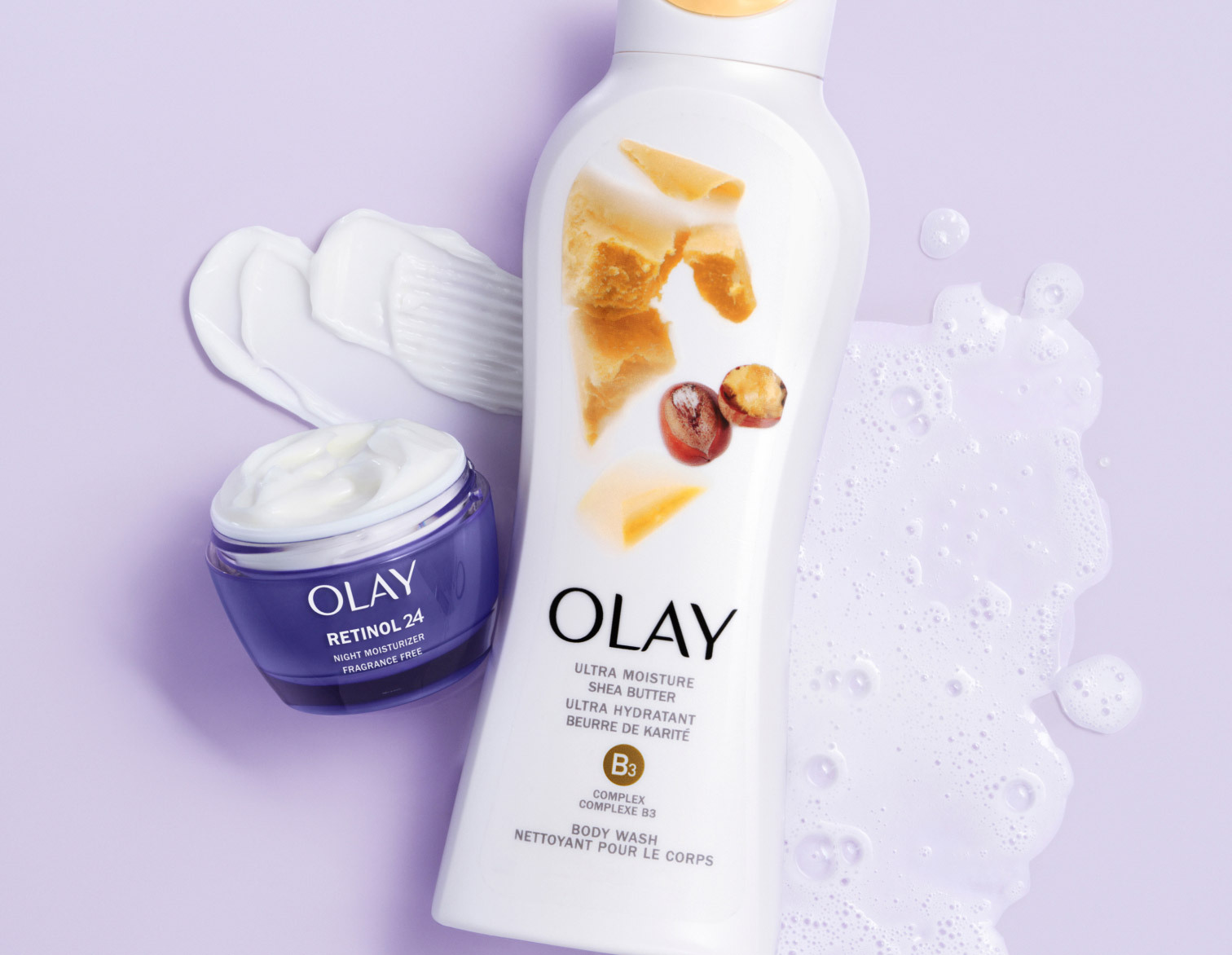 Olay Retinol24 face moisturizer with open lid beside an Olay shea butter body wash on a purple background