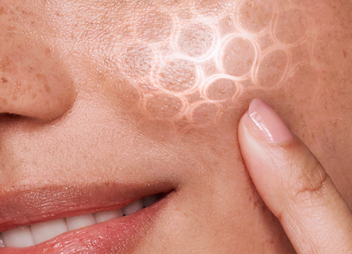 Close up image of a woman’s left check with her index finger on it and a scientific-looking pattern on her cheek to symbolize scientifically proven results on her skin.