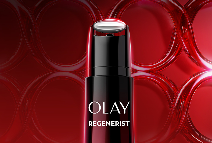 Close up image of the top of the new Olay Face and Neck Treatment to reveal its applicator on a deep red gradient background