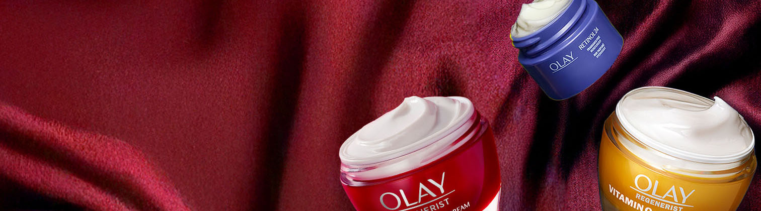 Multiple jars of Olay face moisturizers with their lid open on a velvet red cloth