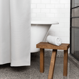 Nebia Shower Curtain in front of a bath tub and a stool