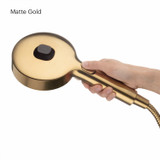 Brondell Nebia Yuba 5-Setting Handshower with hand holding the matte gold HaloNetic Double Docking System displaying rear of showerhead with pause mode button.