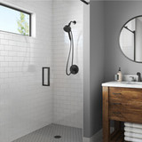 Nebia Merritt 5-Setting Handshower with HaloNetic Double Docking System in matte black installed in a modern bathroom with subway tiles and wooden accents.