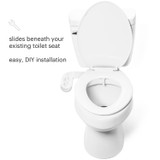 White toilet with open lid and PureSpa Advanced Warm Water Bidet Attachment installed beneath the seat. Text reads: 'Slides beneath your existing toilet seat. Easy, DIY installation.'