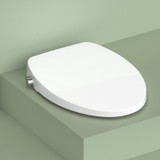 Swash CL150 non-electric bidet toilet seat in white, featuring a slim, modern design with a smooth contoured lid and side-mounted control knob, shown closed on a minimal green studio background.