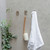 Nebia Multi-Purpose Hook Set Brushed Nickel three pieces in use holding a towel and a loofah in front of a  gray background