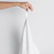 A hand holding the Nebia Hand Towel White in a white background