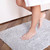 Someone stepping on the Nebia Bath Mat Soft Gray