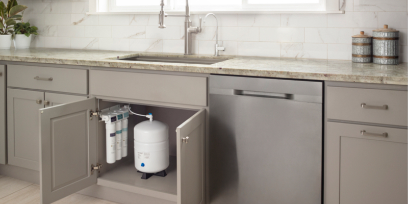 image of clean kitchen with modern farmhouse fixtures.  cabinet doors below sink are open to reveal the Brondell Capella Reverse Osmosis under sink water filtration system.