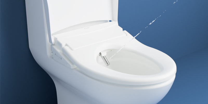 Toilet seat with water spray feature activated, highlighting sleek design and advanced functionality against a clean blue background.