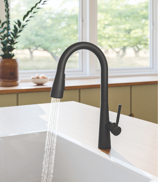 Brondell Jema kitchen faucet in black installed in sunny kitchen with water turned on.