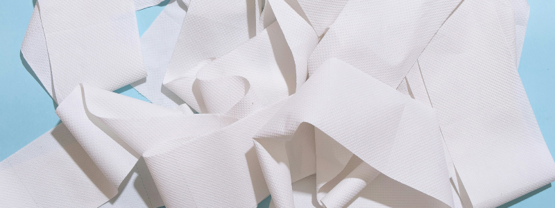 close crop of rolls of toilet paper scattered on hardwood floor