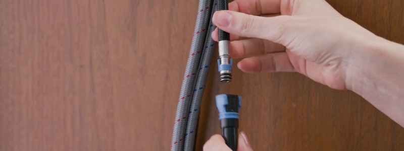 Close-up of hands installing a kitchen faucet beneath countertop, using plumbing tools to secure fittings during a kitchen sink fixture replacement project.