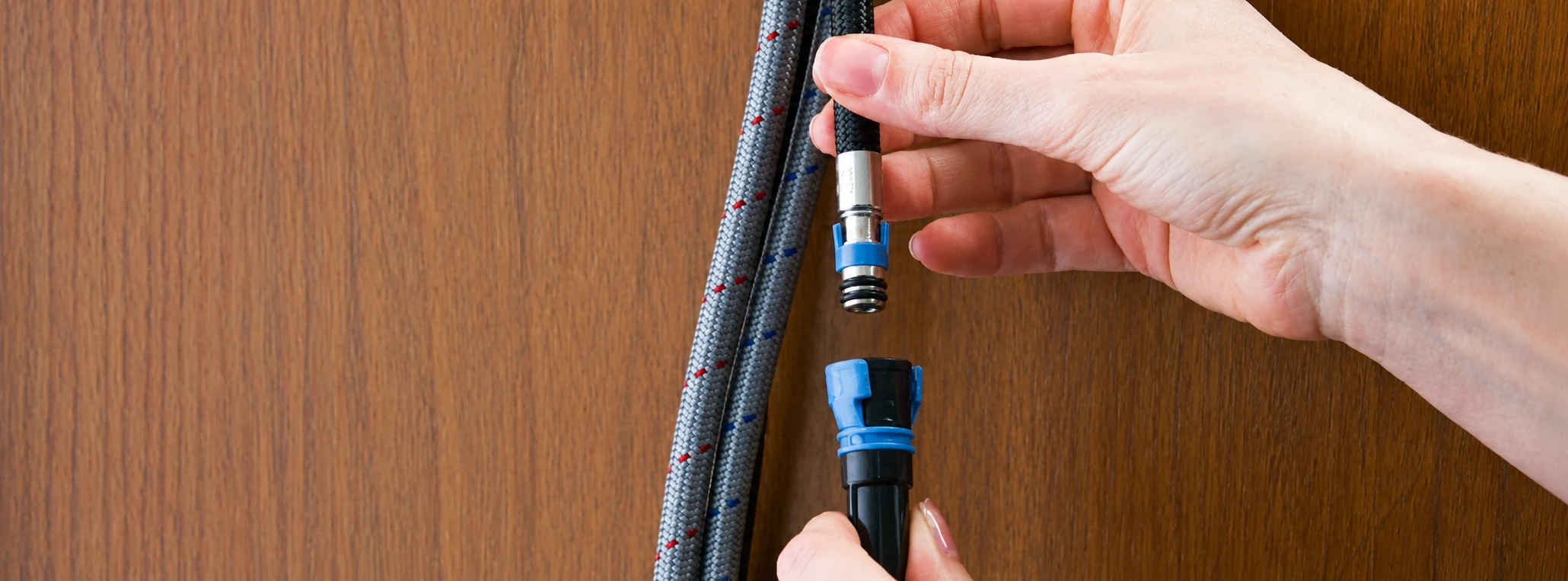 Close-up of hands installing a kitchen faucet beneath countertop, using plumbing tools to secure fittings during a kitchen sink fixture replacement project.