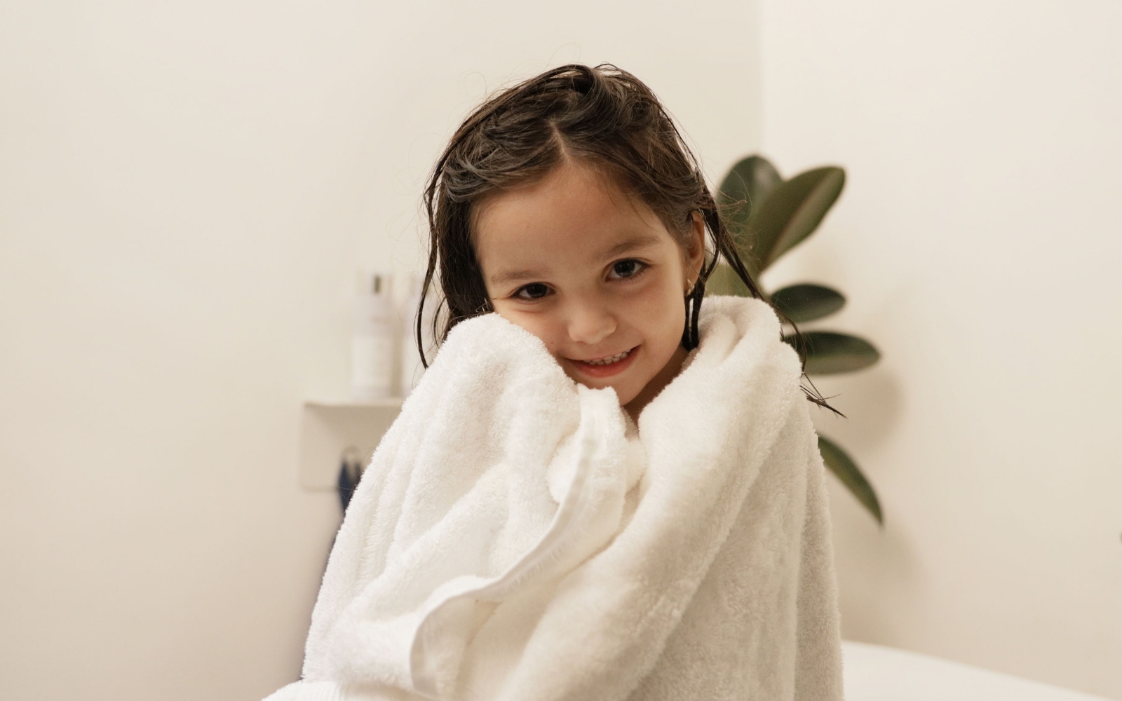 Young girl wrapped in a cozy white Brondell Nebia Bath Towel.