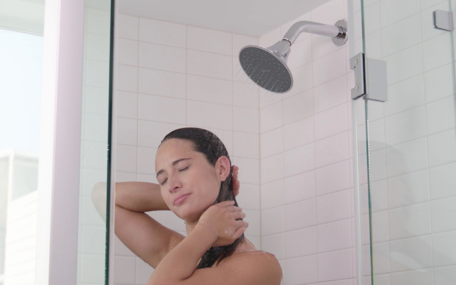 Woman in shower with Brondell Nebia VivaSpring Filtered Showerhead.