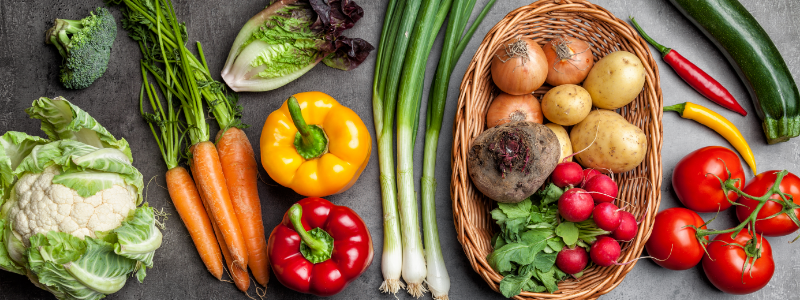 image of fresh vegetables in a rainbow of colors on a dark grey quartz countertop