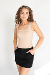 girl wearing tan tank top and black mini skirt