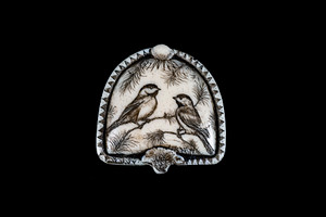 This is a beautiful originally hand etched Chickadees designed pin/pendant. The backing of this piece has the findings to be a pin, as well as a pendant.  They come with an 18" Silver Plated Chain.  This is part of the incredible line of Mossup Valley Designs that we carry, with the wonderful artist Rachel Badeau.  The dimensions of the necklace are 1.36" x 1.36" x 0.34".  The SKU is MVD PN 24.

Rachel Badeau has been etching and engraving in a variety of media for over thirty years.  Her work, characterized by fine line and intricate detail, attempts to touch the hearts and emotions of others.  All while reflecting her love of animals, nature and the human spirit.  

The resin scrimshaw piece is originally hand etched by Rachel Badeau.  We make a mold of the original piece and do an open cast pour of our resin mixture.  The pieces are removed from the mold and sanded and inked.