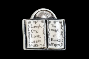 This distinct originally hand etched Magic of Books designed pin/pendant. The design has a book shaped Pin/Pendant, with the saying "Laugh, Cry, Love, Learn.  The Magic of Books".  The backing of this piece has the findings to be a pin, as well as a pendant.  They come with an 18" Silver Plated Chain.  This is part of the incredible line of Mossup Valley Designs that we carry, with the wonderful artist Rachel Badeau.  The dimensions of the necklace are 1.33" x 1.29" x 0.37".  The SKU is MVD PN 21.

Rachel Badeau has been etching and engraving in a variety of media for over thirty years.  Her work, characterized by fine line and intricate detail, attempts to touch the hearts and emotions of others.  All while reflecting her love of animals, nature and the human spirit.  

The resin scrimshaw piece is originally hand etched by Rachel Badeau.  We make a mold of the original piece and do an open cast pour of our resin mixture.  The pieces are removed from the mold and sanded and inked.