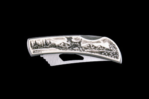 This stunning originally hand etched Jumping Deer design on a Stainless Steel Silver Hawk Knife.  The back of the knife has a belt clip and all the knifes come with the pictured sheath.  It is a lock blade knife and a useful pocket knife.  The artwork was originally hand etched by Linda Layden.  The dimensions of the Silver Hawk knife with the blade closed are 3.00" x 0.96" x 0.55".  The blade itself is approximately 2.35" making the width of the knife with an open blade 5.35".  The SKU is NC 14 - 103A.

Linda Layden has been making beautiful works of art in the scrimshaw field for over 40 years.  Originally a hobby that became a full time job.  Her work can be found in gift shops, galleries and museums across the world.