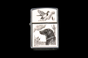 This is a unique originally hand etched Eco-Ivory Black Lab designed Zippo Lighter! The top of the flip lighter has a a Duck flying away.   The Zippo is a Brushed Chrome finish. Each lighter has a bottom stamp signifying the year it was made, is refillable. All windproof lighters are American made in Bradford, PA factory and come packaged in a gift box.  This is part of the Save the Elephant Collection and was originally hand etched by Linda Layden. The SKU is NC 54 - 142

The Zippo Lighter is 2.24" x 1.51" x 0.59".  It weighs 2.04 oz.