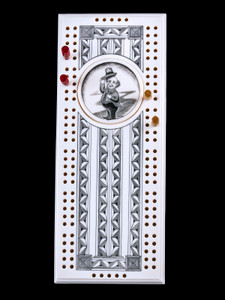 This wonderful two person and our two team cribbage boards is a beautiful accent piece for your home or take it on the road for use as a travel cribbage board.  With the magnet holding the center piece and pegs in place it is a stunning travel cribbage board. 

This is a unique originally hand etched Leprechaun Eco - Ivory Scrimshaw Cribbage Board!   The center circular piece has a magnet holding it in place.  Pushing on the base of the piece pops the Large round off the board, where the pegs are stored.  All cribbage boards come with 3 red and 3 white/yellow wooden pegs. 

The cribbage board itself is made for two players or teams.  The board has a native geometric design that was originally hand etched.  The large round piece has a magnet on the back to keep it secured to the board and store the pegs.  The pegs are made of wood.  This is part of the Save the Elephant Collection and was originally hand etched by Linda Layden.  The SKU is NC 53 - 176.

The Cribbage Board is 8.50" x 3.46" x 0.46".  It weighs 11.28 oz.